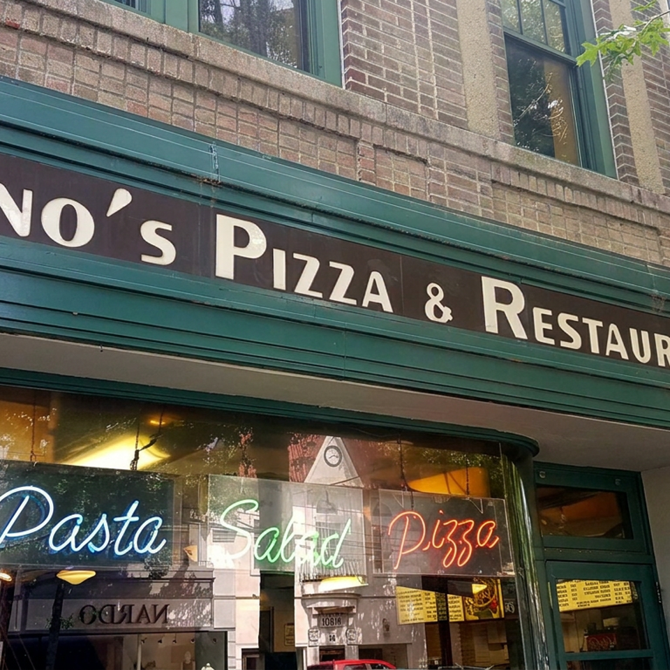 Exterior storefront of Cino’s Pizza & Restaurant with neon signs advertising pasta, salad, and pizza.